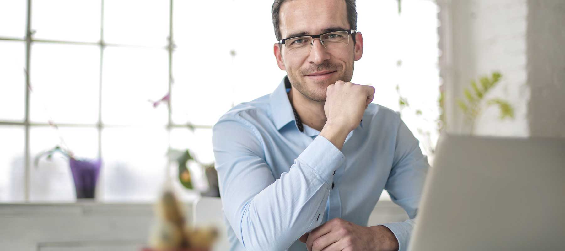 Jeune homme devant son bureau portant des lunettes