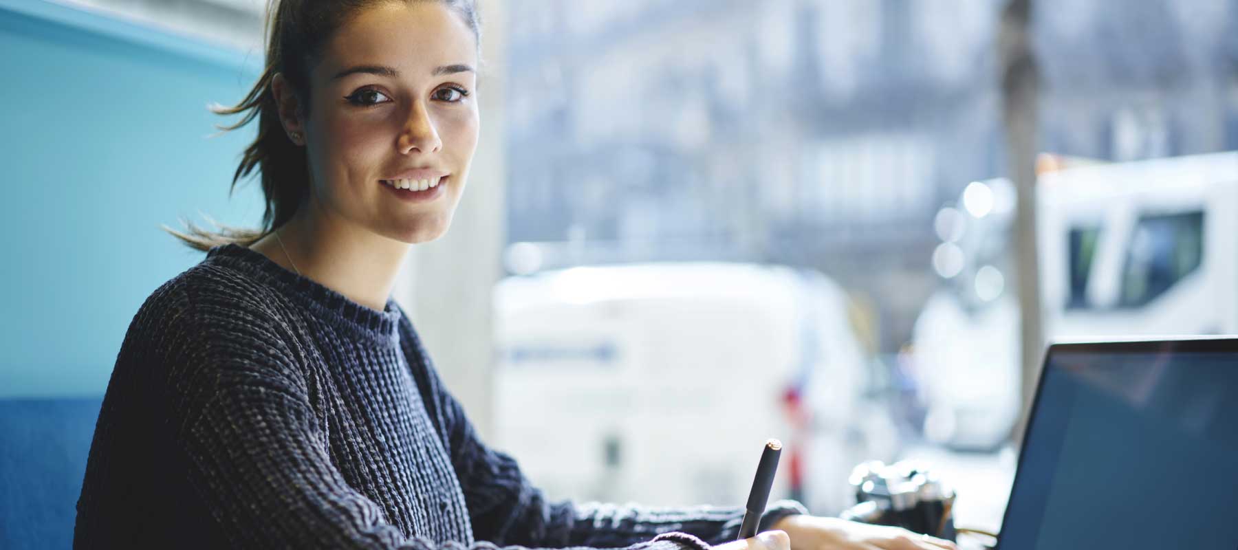 Jeune femme souriant devant son ordinateur